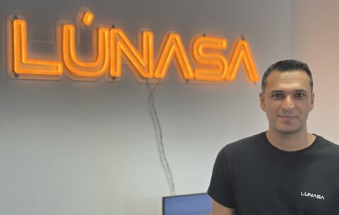 Headshot of Amin Chabi stood in front of a Lunasa sign
